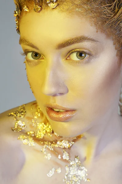 Portrait of fashion model with gold foil on face and hair