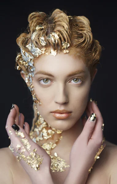 Portrait of beautiful model with shiny foil on face and hair