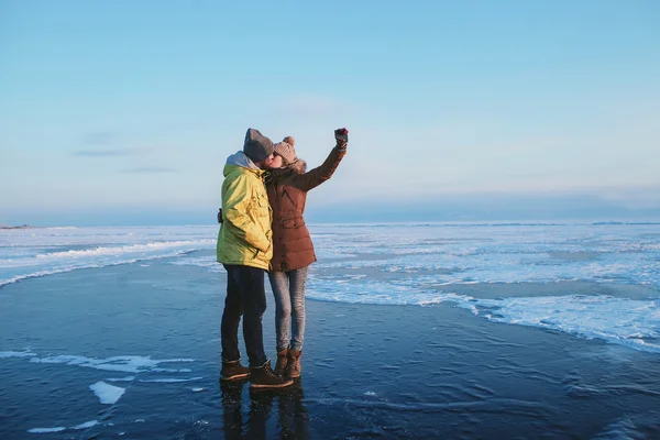 Young couple is doing selfie on the ice of the frozen lake