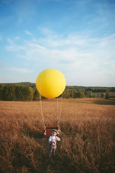 Little boy traveler standing next to a aerostat in field