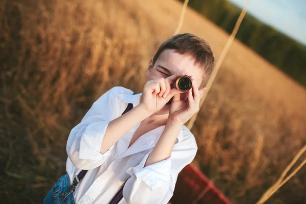 Boy traveler looks through a telescope in a field
