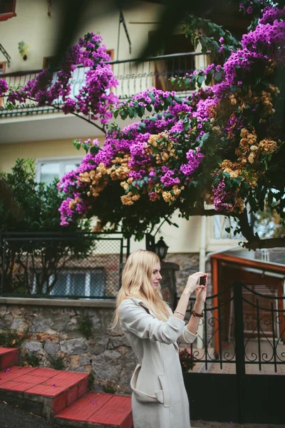 Girl walking down the street past the house with the fence and flowering tree