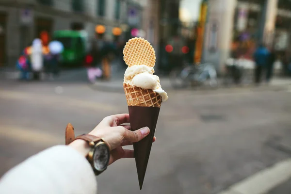 Female hand holding a cone with ice cream