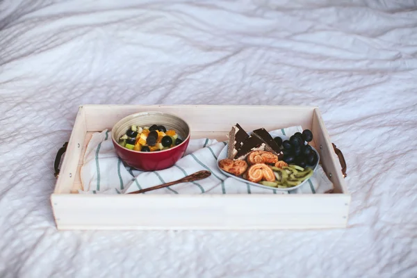 Breakfast on a tray, cereal with fruit on the bed