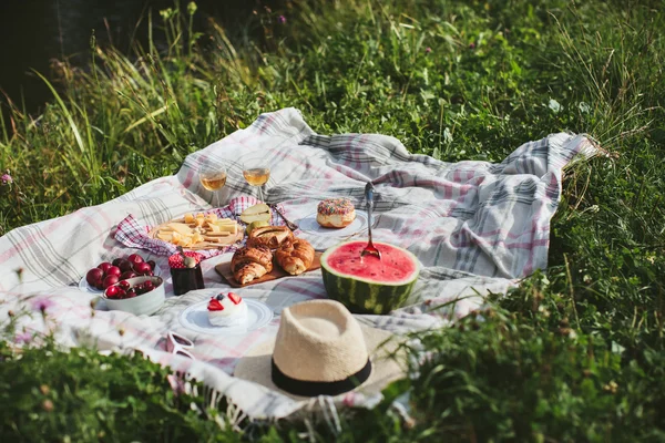 Summer picnic on the rug. Fruits, berries, pastries and cheese