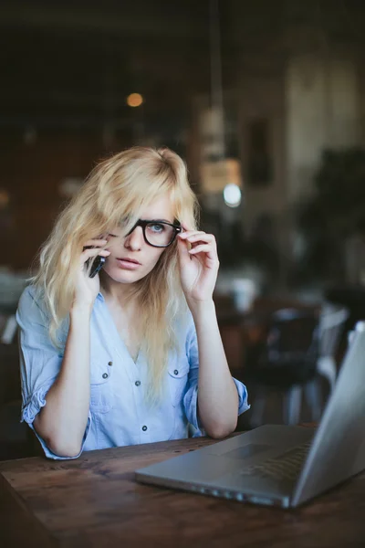 Business woman working at a laptop and talking on the phone