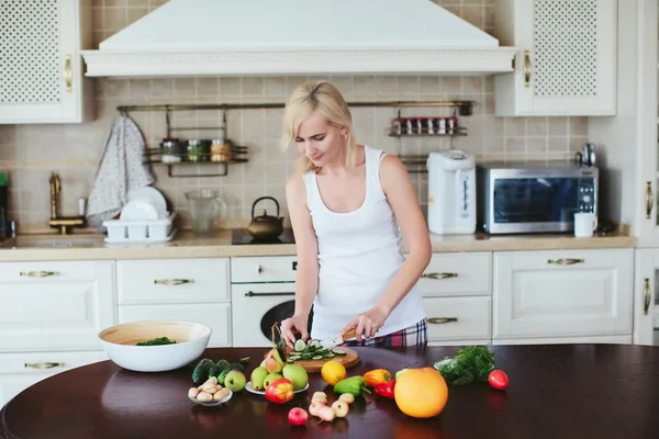 Woman in a home clothes prepares vegetarian salad in the kitchen