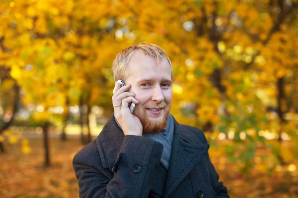 A man in a coat talks on the phone