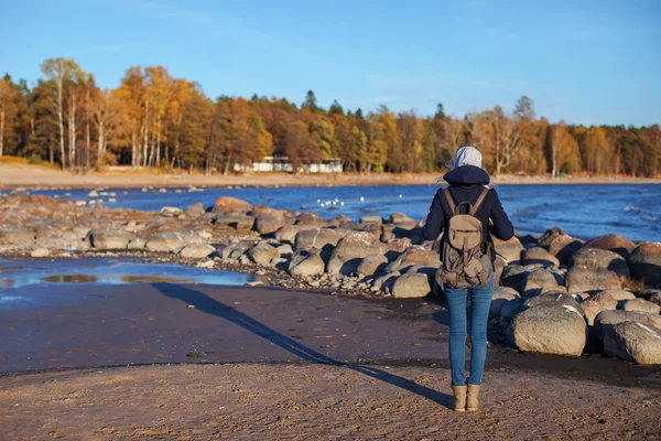 Girl with a backpack standing with her back to the shore