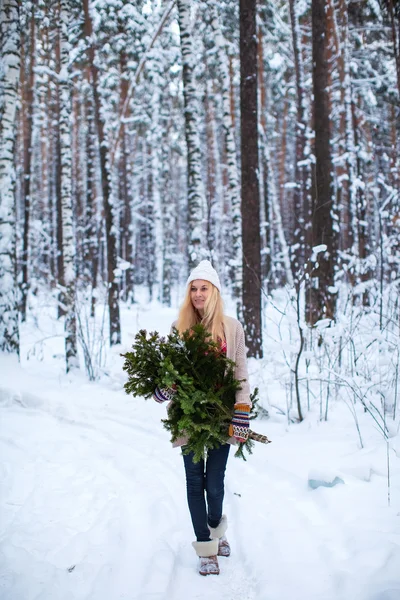 Girl keeps fir branches in the winter forest