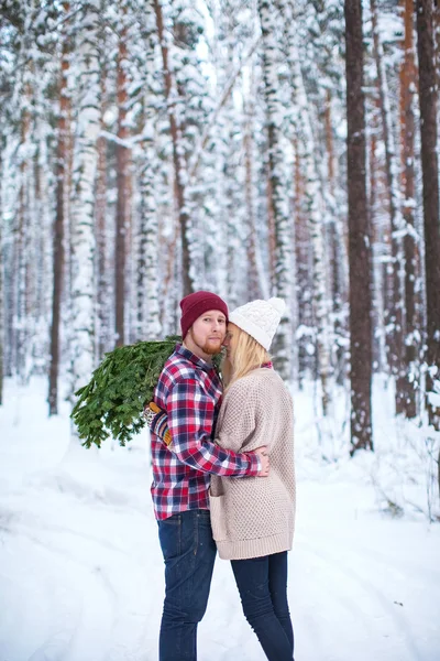 Young couple with fir twigs walk in the winter woods
