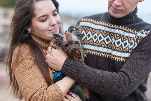 Couple holding a small dog in her arms on the rocky beach