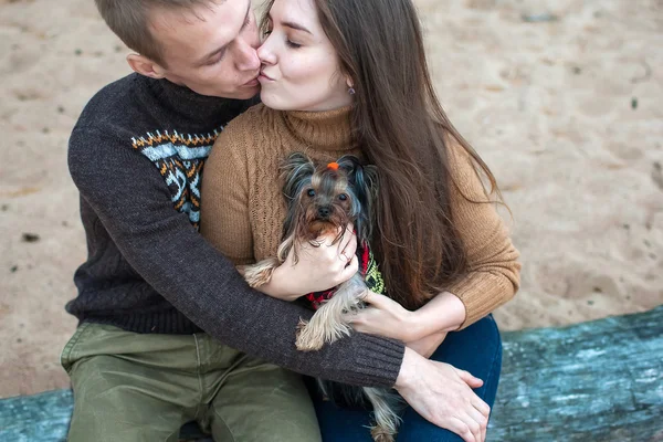 Young couple holding a dog in her arms on the rocky beach
