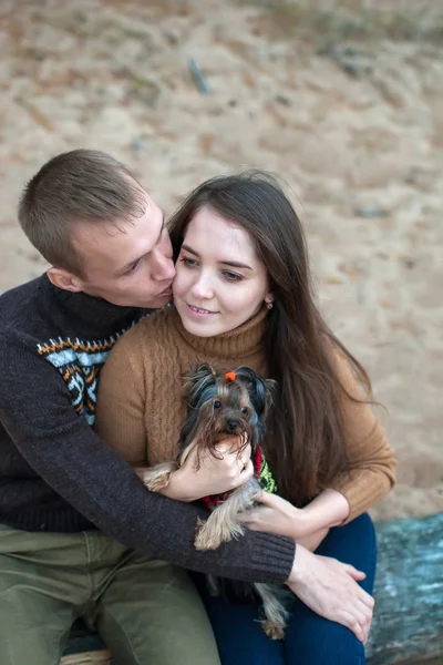 Young couple holding a dog in her arms on the rocky beach