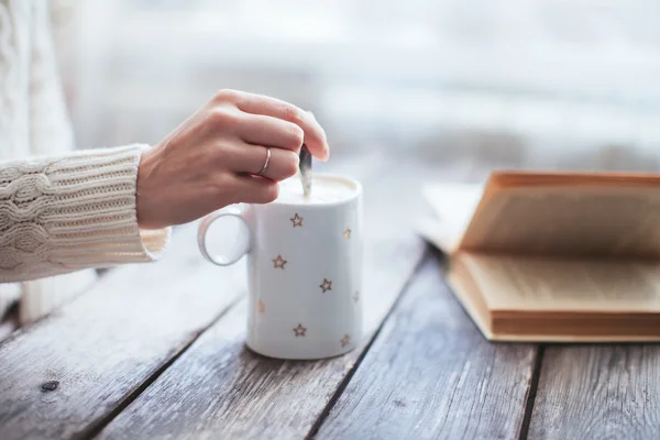 Female hand stir coffee on wooden table