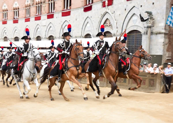 Performance of cavalry on parade before start of annual traditional Palio di Siena horse race in medieval square \