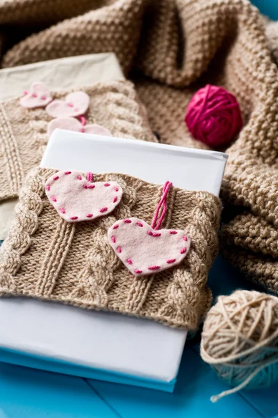 Two old pads in knitted cover with felt hearts lie next to the c
