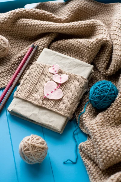 One old notebook in knitted cover with felt hearts lie next to t