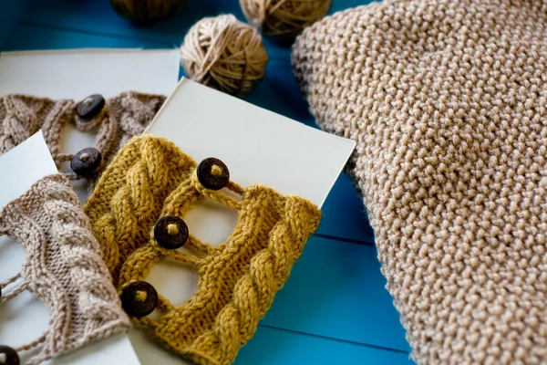 Soft knitted blanket, yarn balls lying on blue background