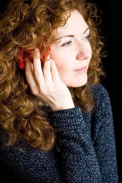 Portrait of beautiful young redhead with curly red rose