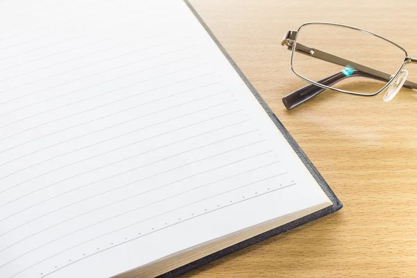 Eyeglasses and open note book with blank page