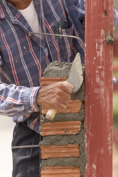Bricklayer working in construction site of brick wall