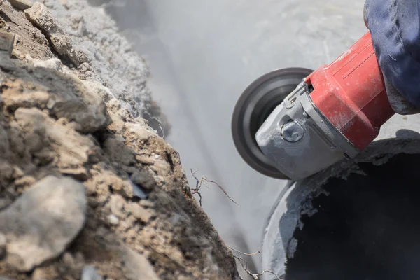 Plumbers cutting concrete water pipes