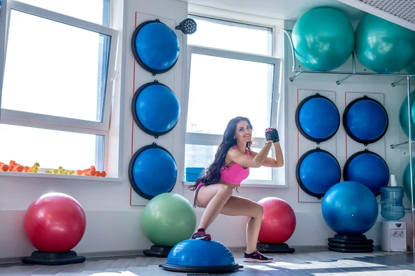 Smiling pretty woman doing squats at gym