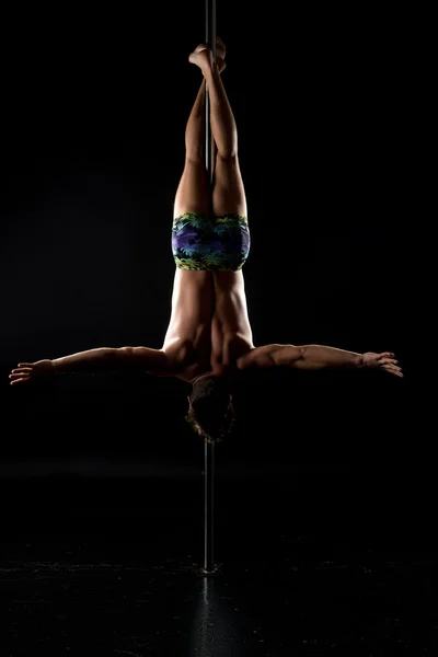Pole dance. Shot of strong man hanging upside down