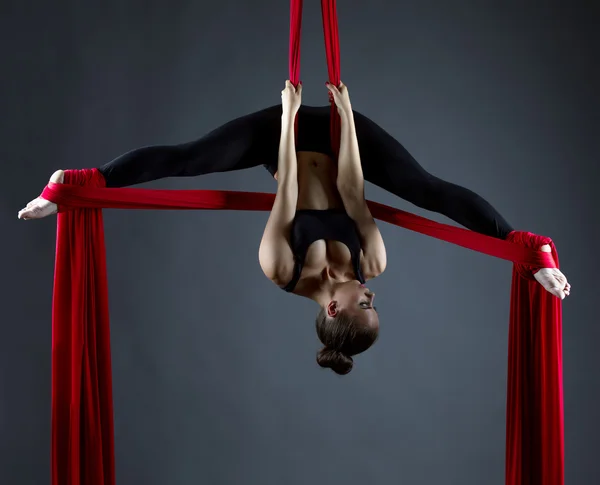 Sexy female acrobat performs hanging upside down