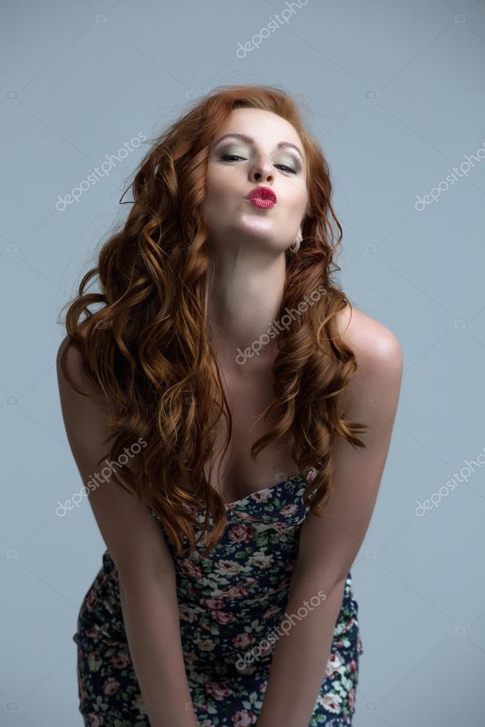 カメラにキスを吹く赤髪ファッション モデル。スタジオ写真 \u2013 ストック画像