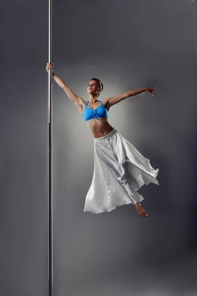 Pole dance. Beautiful girl spinning around pylon