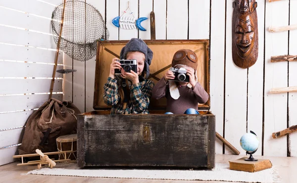 Two little girls in wooden chest playing rarity cameras