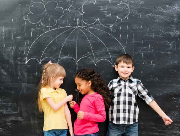 Three funny children with umbrella drawn on the blackboard