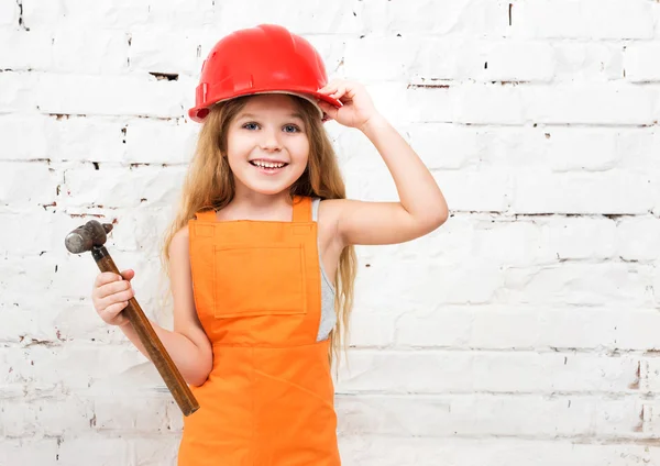 Cute little girl in repairman uniform and hammer in hand