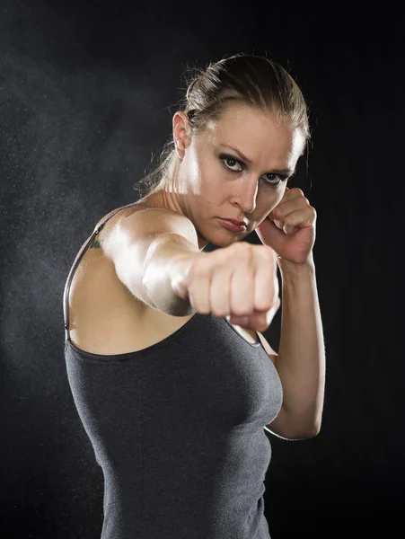 Female Fighter in Combat Pose Against Black