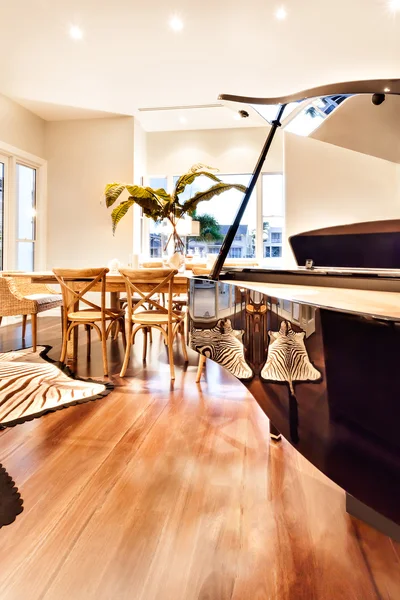 Wooden glossy piano with a dining table and zebra printed floor