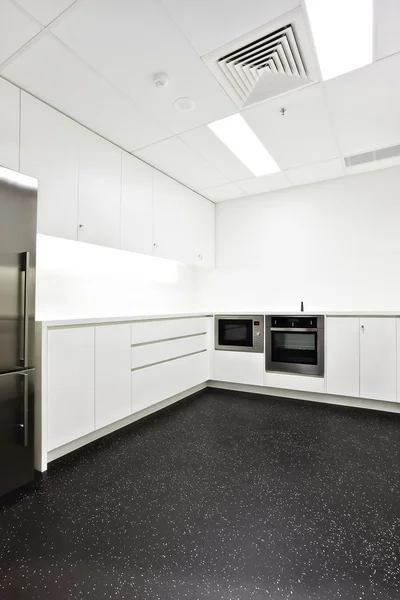Modern kitchen with white walls and black floor tiles