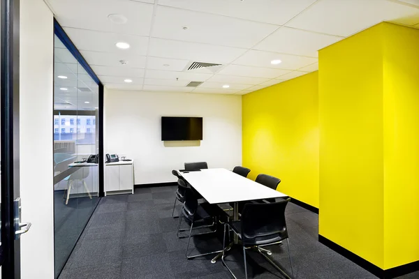 Small meeting room with yellow walls and tv