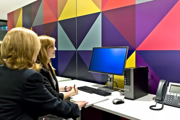 Business women in a computer room looking at a monitor