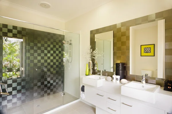 A stylish modern washroom with a glass shower and mirrors on sid