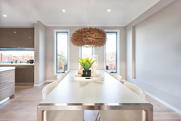 Interior of a modern dinning room with a long white table and ba