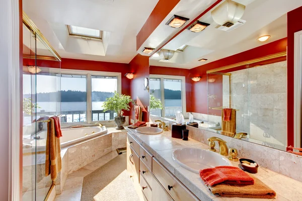 Red and marble interior of large luxury master bathroom with gla