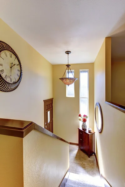 House interior, yellow split level hallway with clock.