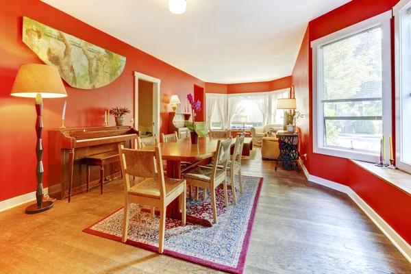 Red dining room interior with old wood piano and living room are