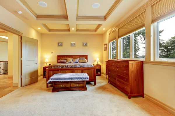 Luxurious big bedroom with wooden bed, vanity cabinet, trimmed ceiling.
