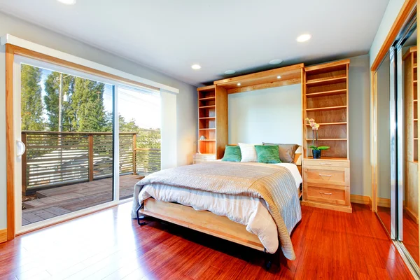 Bright bedroom with storage combination, hardwood floor and glass door.