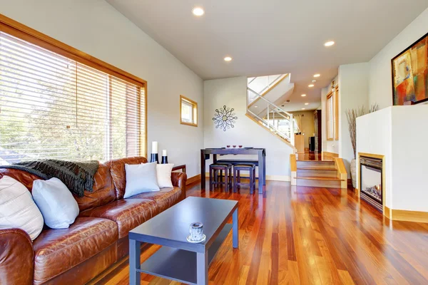 Cozy living room with brown leather couch, fireplace, hardwood  floor.