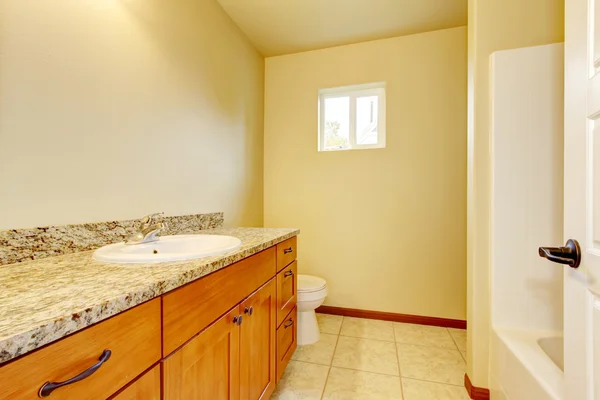 Bathroom interior with vanity cabinet, granite counter top, tile floor.