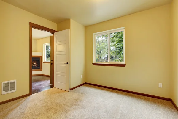 Bright small empty room with carpet floor, one window and ivory walls.
